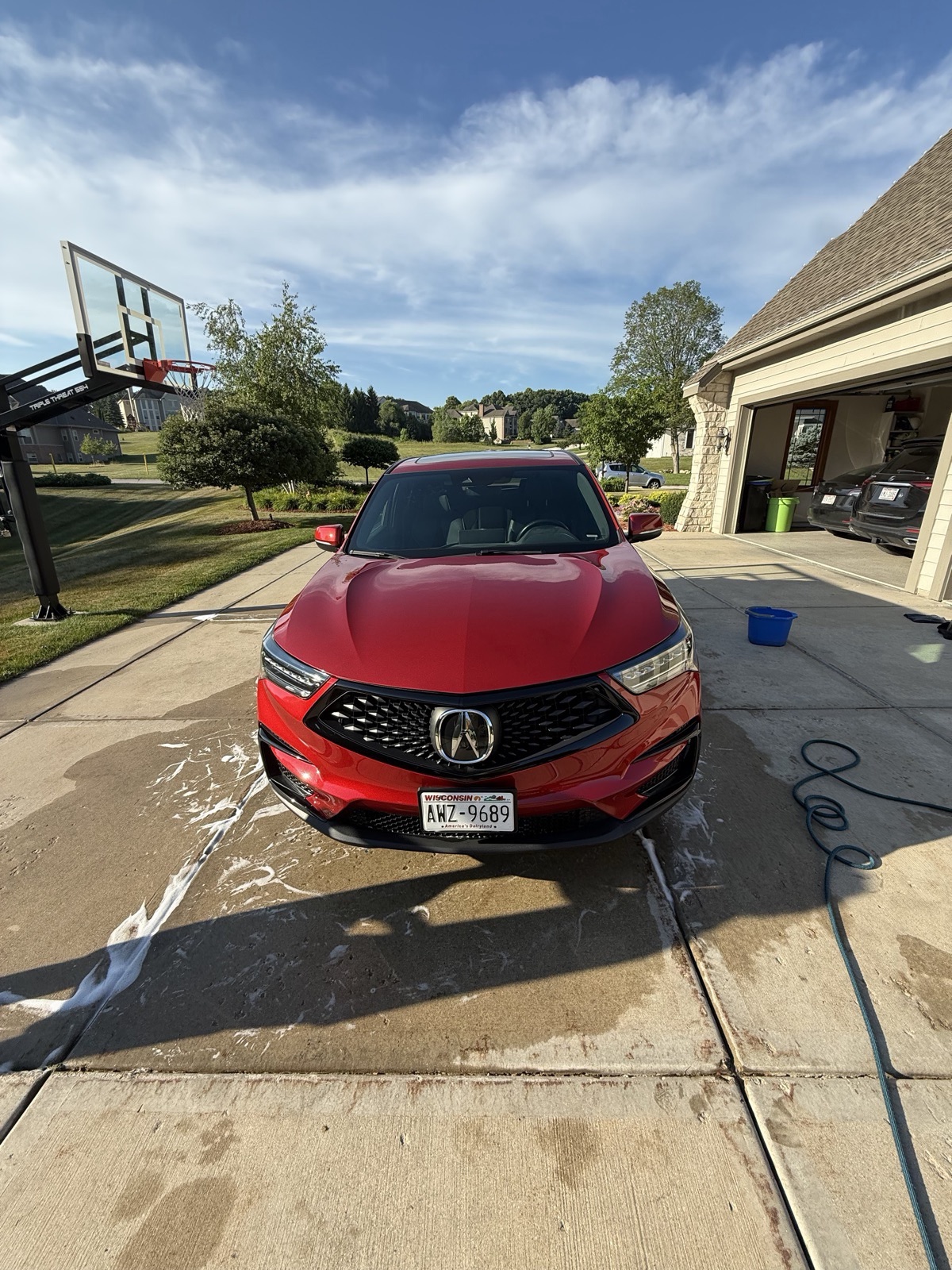 Red SUV mid-detail with suds rinsed off the paint