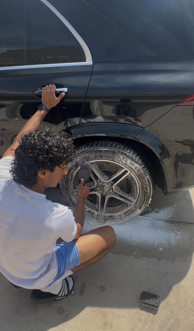 Detailer cleaning a Mercedes AMG wheel, foam on the tire